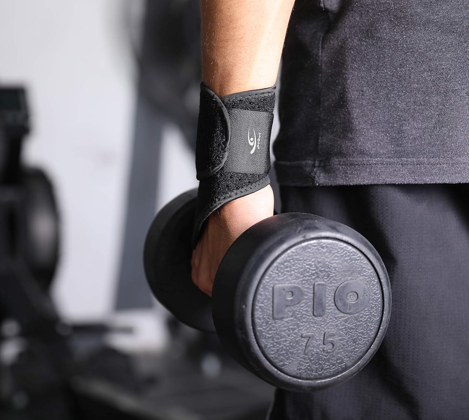 Person holding a black dumbbell with 'Pio' branding in a gym setting