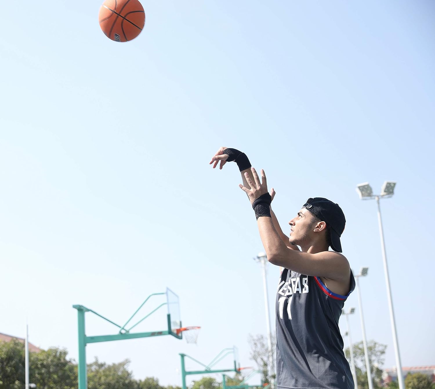 Person playing basketball outdoors with a clear sky